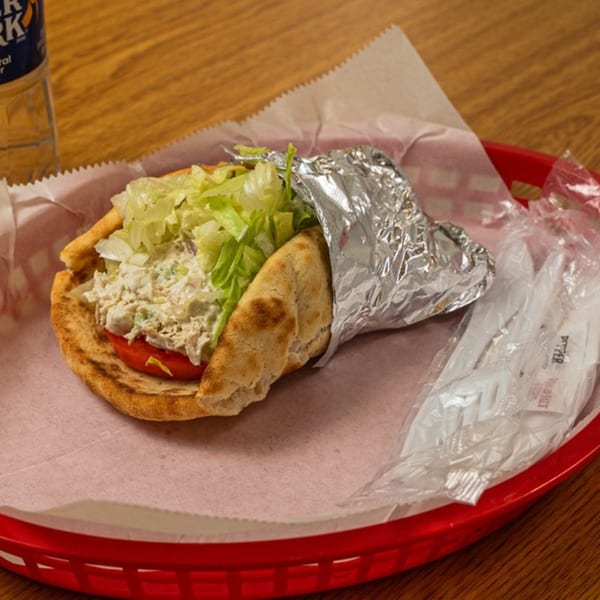 Phillys Cafe & Deli chicken salad pita with lettuce and tomato in a red basket.