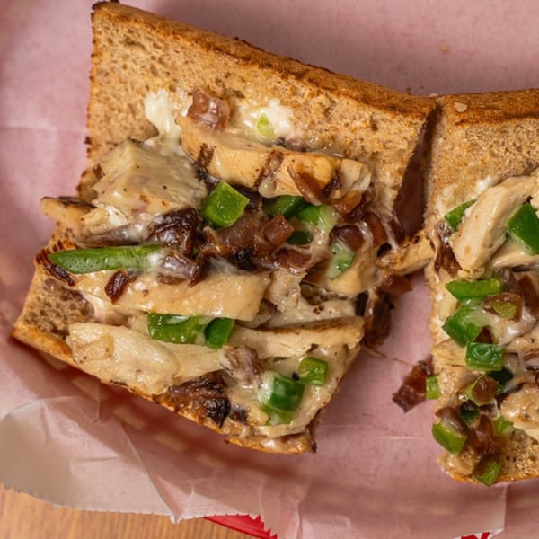 Phillys Cafe & Deli's chicken cheesesteak sandwich with melted cheese, green peppers, and caramelized onions.
